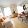 Bright living room with sofa, dining table and kitchenette.