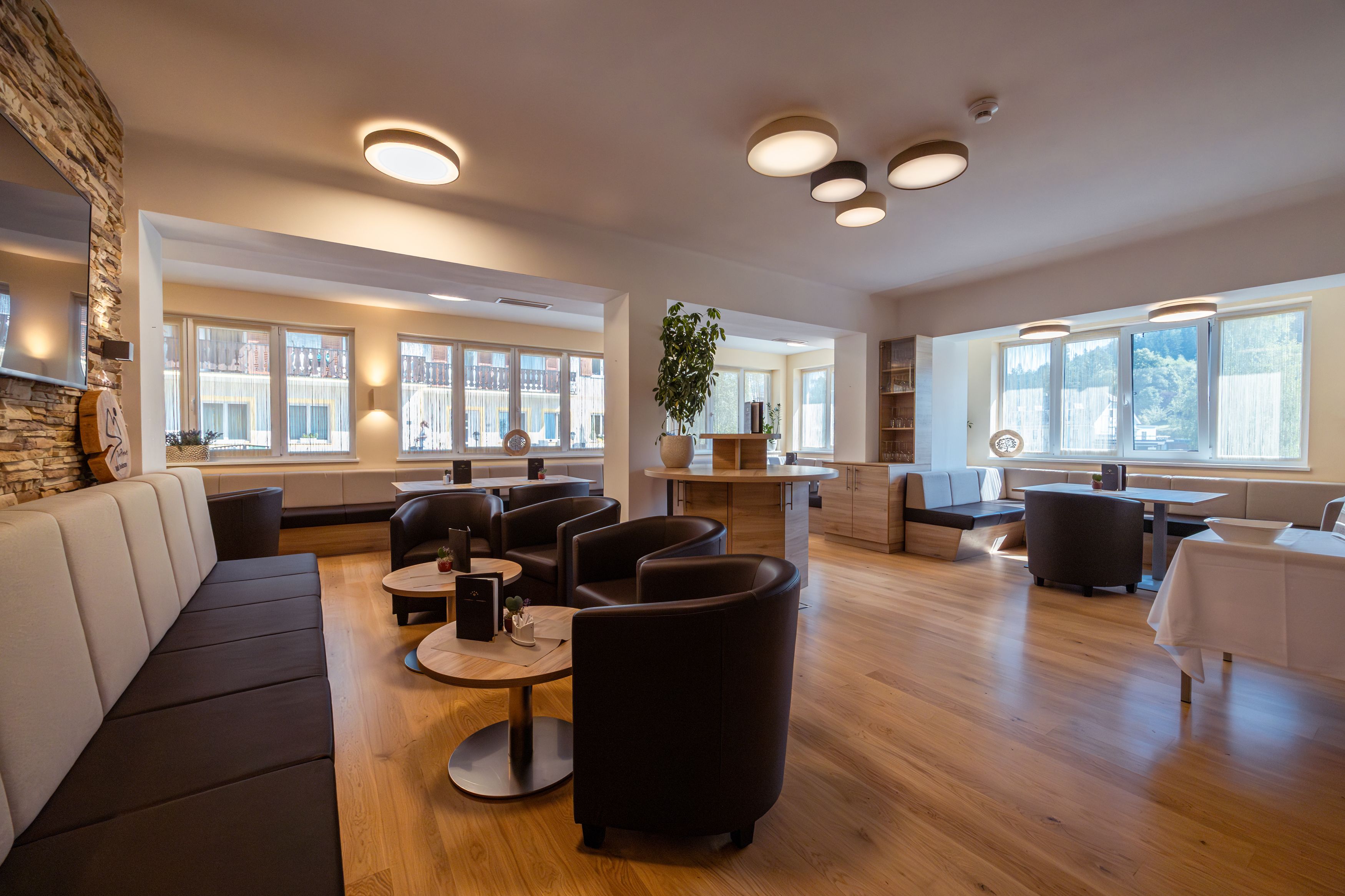 Innenansicht einer modernen Hotel-Lounge mit Sitzgelegenheiten und großen Fenstern.
