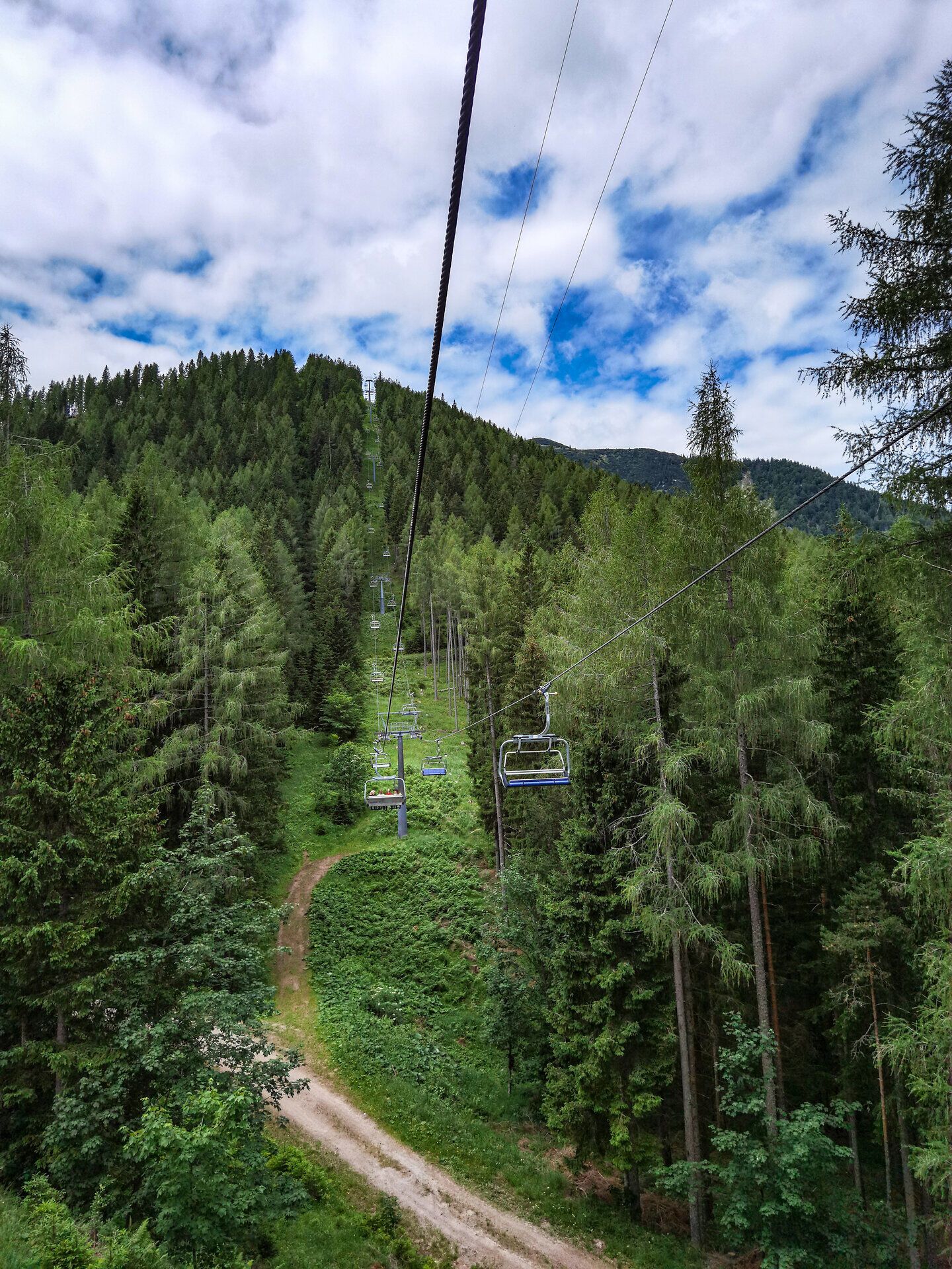 Die sanften Hügel und dichten Wälder laden zu einer entspannenden Fahrt mit dem Sessellift ein. Über den Baumwipfeln schimmert der Himmel in verschiedenen Blautönen und verspricht unvergessliche Ausblicke auf die umliegende Berglandschaft. Hier wird der Sommer in den Bergen zum Erlebnis für alle Naturliebhaber.