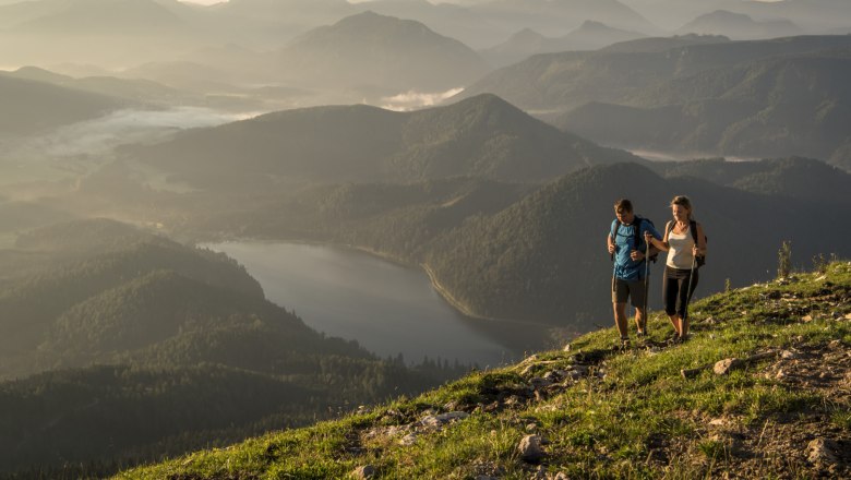 Mann und Frau wandern auf der Gemeindealpe. Im Hintergrund sieht man Berge und den Erlaufseee.