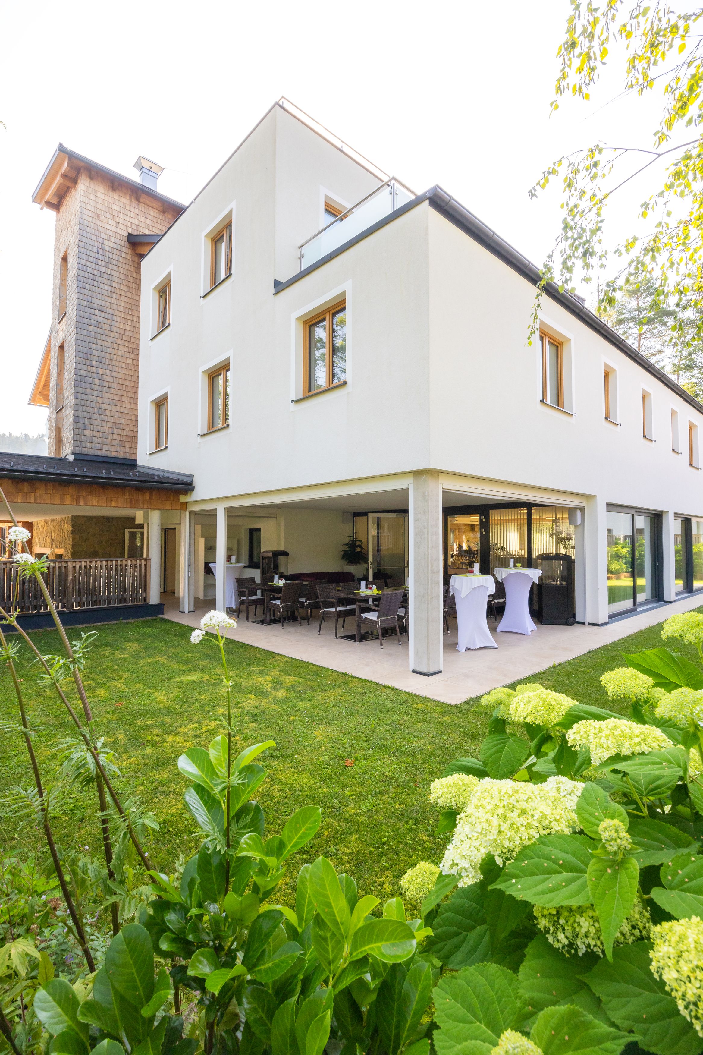Außenansicht eines modernen Hotels mit Terrasse und Garten.