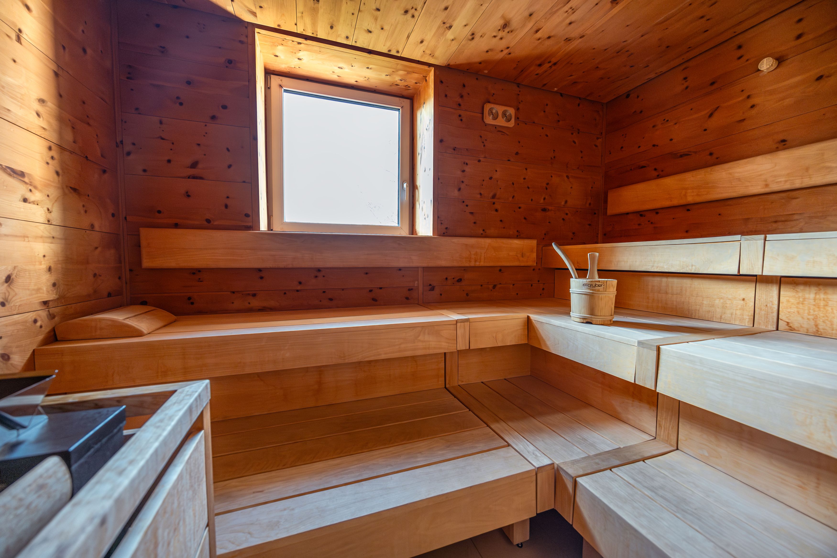 Innenansicht einer Holzsauna mit Fenster und Saunaeimer.
