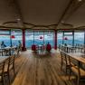 Innenansicht eines modernen Restaurants mit Panoramafenstern und Bergblick.