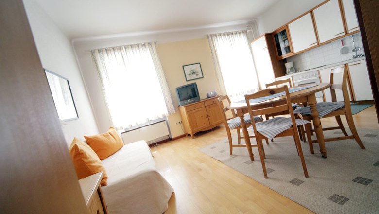 Bright living room with sofa, dining table and kitchenette.