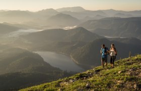 Mann und Frau wandern auf der Gemeindealpe. Im Hintergrund sieht man Berge und den Erlaufseee.