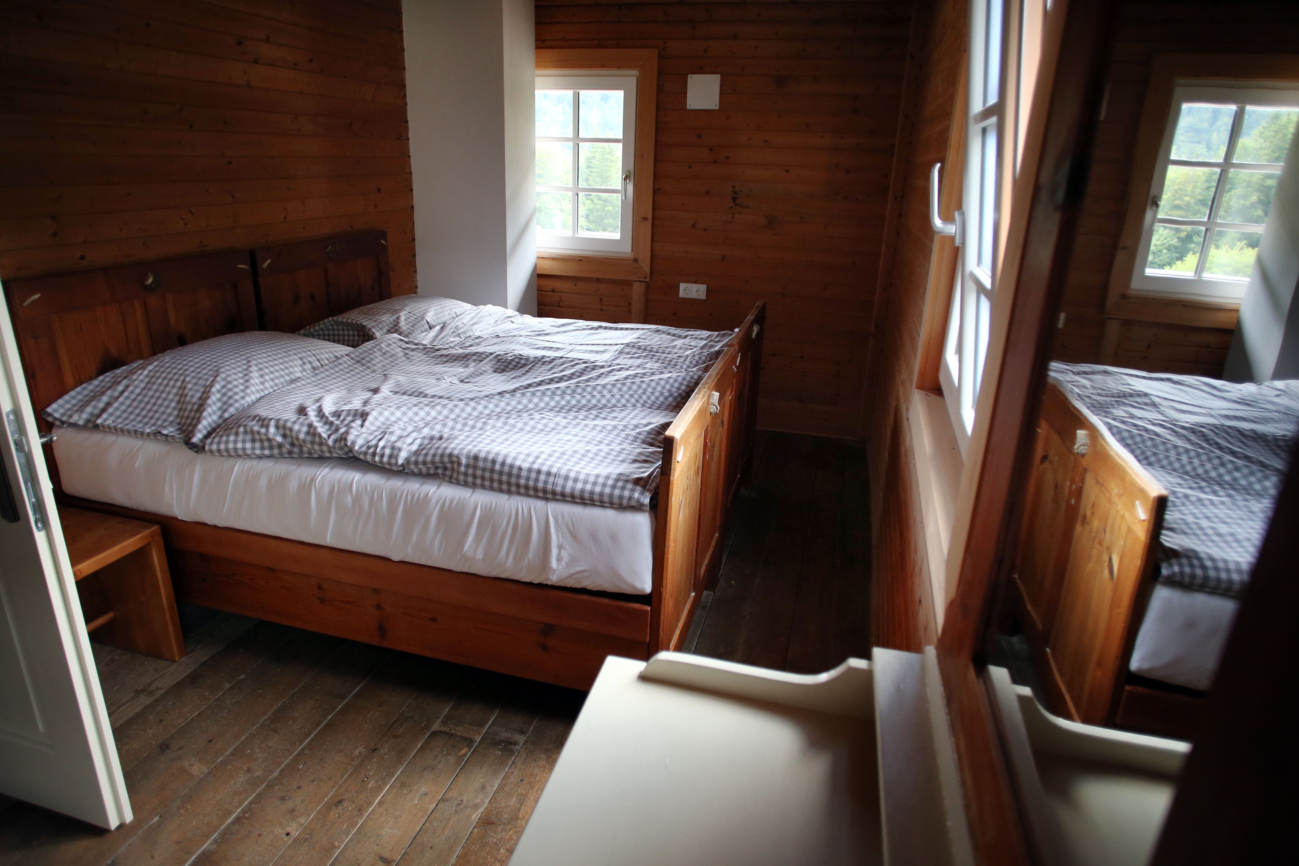 Ein gemütliches Zimmer mit Holzwänden und einem Doppelbett im Schutzhaus Vorderötscher.