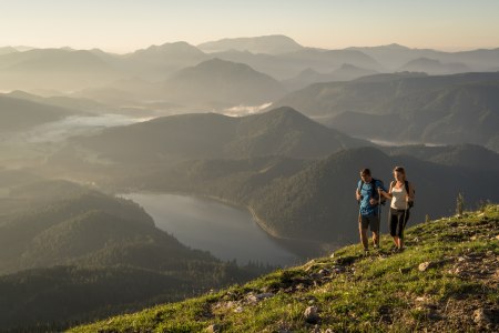 Mann und Frau wandern auf der Gemeindealpe. Im Hintergrund sieht man Berge und den Erlaufseee.